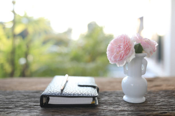 istock pink roses in a white vase and leather notebook on wooden table 1436420557