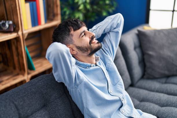 istock Young hispanic man relaxed with hands on head sitting on sofa at home 1436422625