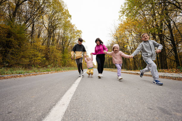 istock Mother with four kids running on road at autumn fall forest. 1436423746