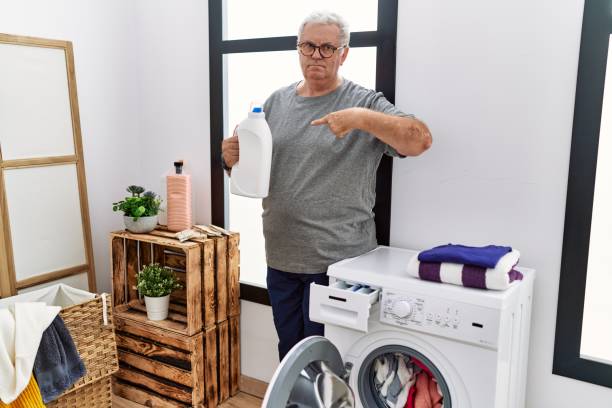 istock Senior caucasian man doing laundry holding detergent bottle pointing finger to one self smiling happy and proud 1436424158