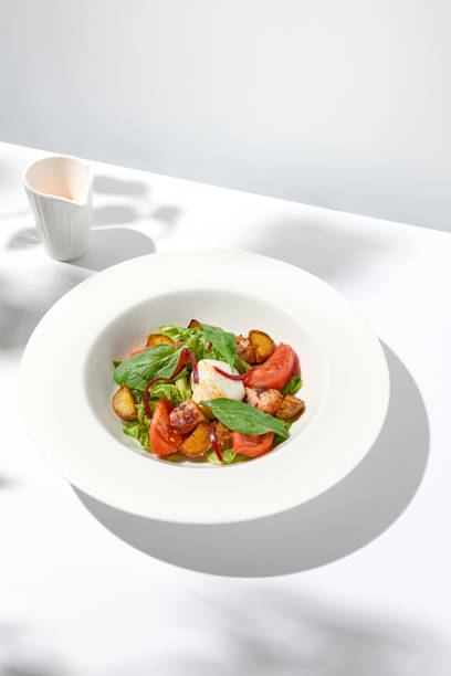 istock Salad with octopus, baked potatoes and poached egg on white table with hard shadows. Seafood salad with vegetables and potatoes in summer menu restaurant. Octopus and eggs salad in modern style. 1436425669