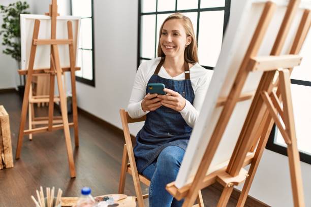istock Young caucasian woman smiling confident using smartphone at art studio 1436426851