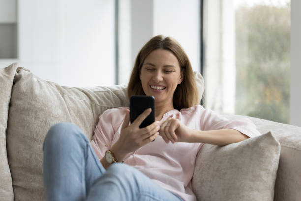 istock Pretty woman relaxing on cozy sofa with modern smartphone 1436427114