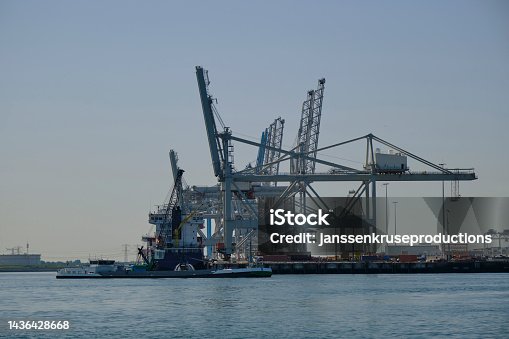 istock ROTTERDAM, THE NETHERLANDS - New container terminal with a very large container ship and in the foreground a smaller inland container ship on the Maasvlakte of the port of Rotterdam 1436428668