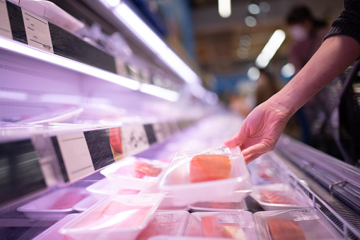 Woman buying fish fillet in supermarket