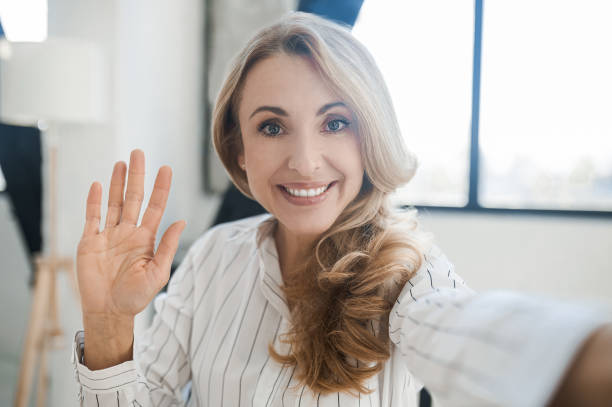istock Blonde woman smiling and waving her hand 1436429284