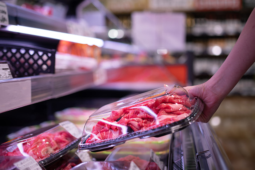 Woman picking up meat in a supermarket