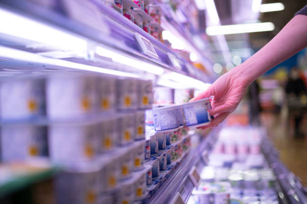 Woman picking up yogurt in a supermarket Woman picking up yogurt in a supermarket rigging stock pictures, royalty-free photos & images