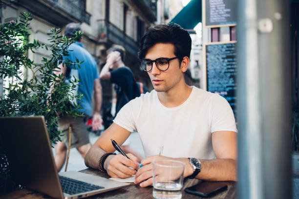 istock Serious caucasian man in eyewear for vision protection learning via online course making notes in notepad, pensive handsome male student watching training educational webinar on cafe terrace 1436432832