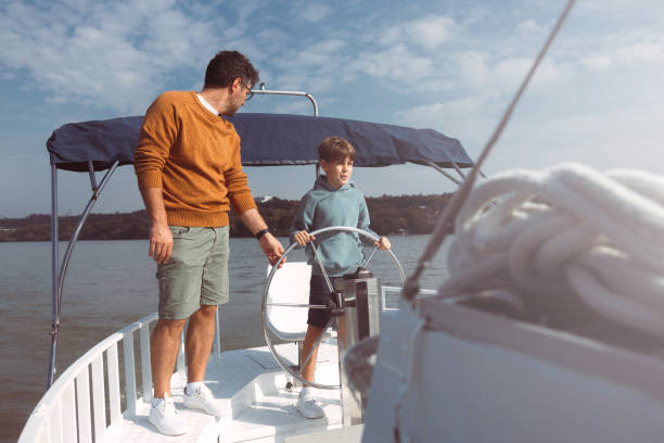 istock Father and son together steer a ship sailing on a river 1436433664