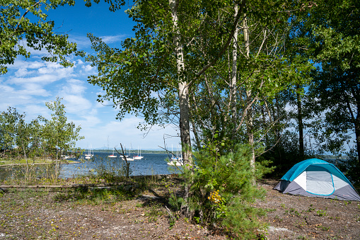 Tent set up on a campground near a bay with anchored sailboats at lake champlain