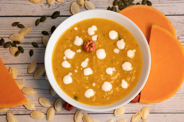 Pumpkin soup with cream and pumpkin seeds isolated on wooden background. stock photo