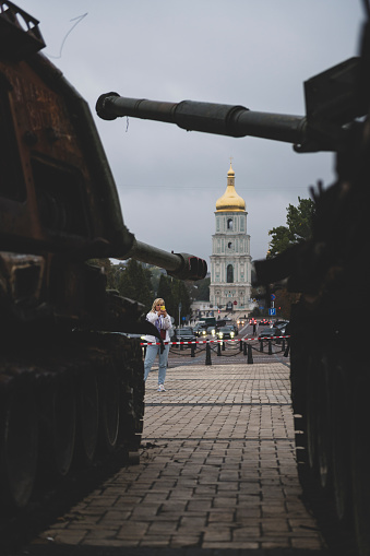 Kyiv, Ukraine - September 13, 2022: A woman takes a picture of two of the several destroyed Russian armoured vehicles that were put on display in Saint Michael's Square in Kyiv.