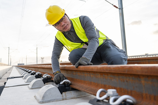 A Chinese male engineer works at a railway construction site under construction.