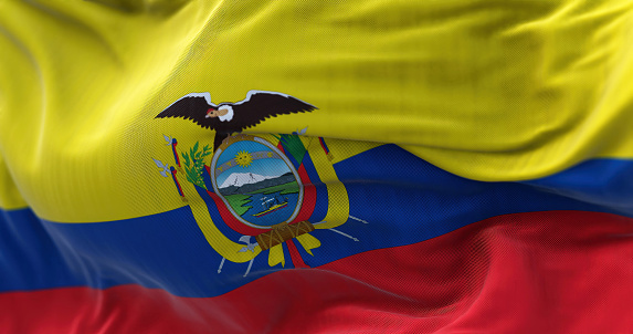 Close-up view of the Ecuador national flag waving in the wind. The Republic of Ecuador is a presidential republic of South America. Fabric textured background. Selective focus