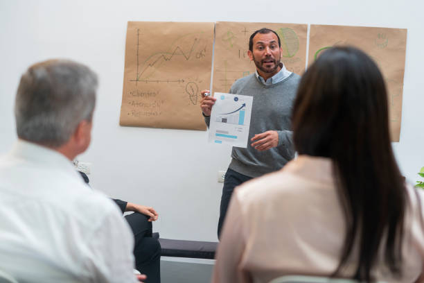 istock latin business man inside his work office giving a brief explanation to his co-workers 1436445328