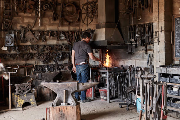 istock Fire, workshop and manufacturing with a man blacksmith working in a forge for metal work or industrial production. Industry, flame and plant with a male worker busy in a foundry on his metallic craft 1436445435