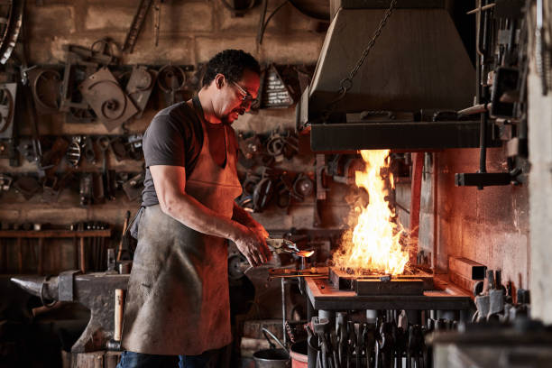 istock Metal worker, engineer and welder working in a welding workshop or factory while melting iron in a furnace. Steel manufacturing or blacksmith male in warehouse using equipment and skill for metalwork 1436445457