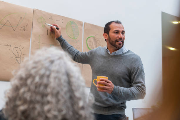 istock latin business man inside his work office giving a brief explanation to his co-workers 1436445520