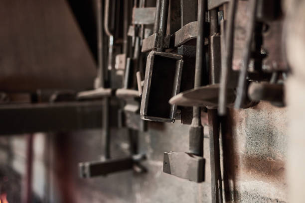 Background of blacksmith metal tools on wall in workshop, empty steel construction factory and manual labor manufacturing process. Closeup rusty iron equipment of production, maintenance and building