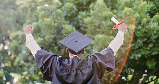 istock Graduate, success and education, celebrate graduation with certificate and pride for achievement. Winner, fist and academic event, degree with college diploma and happiness outdoors in cap and gown. 1436450622