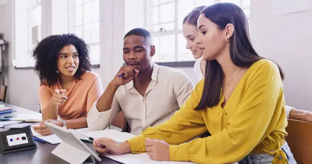 Photo of Teamwork, meeting and tablet with a business woman and her designer team working at a desk in their office. Strategy, collaboration and vision with an employee group at work on the company mission