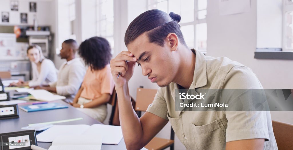 Stress, fail and education with a man student writing an exam with learning difficulty in a university classroom. Study, scholarship and college with a young male pupil feeling burnout in class Disappointment Stock Photo