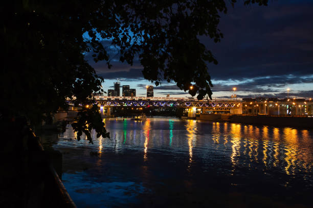 Night view of the river and the bridge over it. A small boat floats on the river.