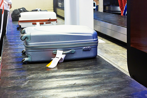 Travelers' bags arriving on the baggage carousel at an airport.