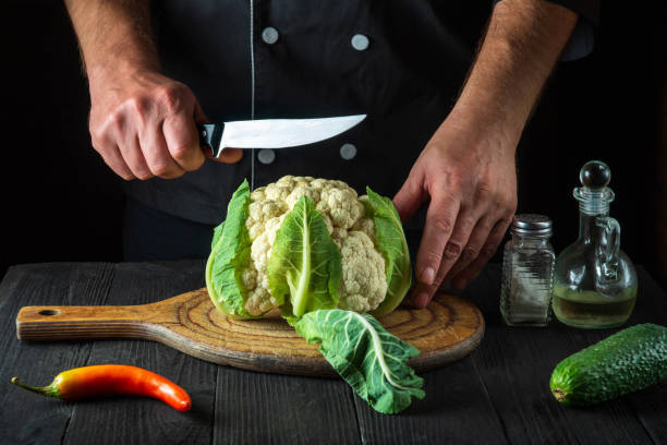 chef profissional está cortando couve-flor em uma cozinha de restaurante. a ideia de uma deliciosa dieta para o café da manhã ou jantar - hotel commercial kitchen organic salad - fotografias e filmes do acervo