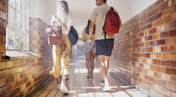 istock College, university and students walking in hallway for a lecture, class test or exam for knowledge. Friends with education scholarships back to school in the corridor talking on campus, back view 1436459489