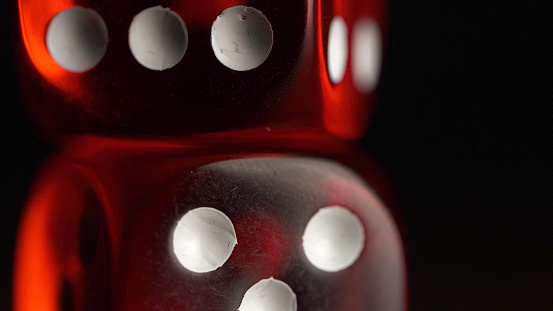 Red dices on black background. Red dice standing on each other, macro on black background.