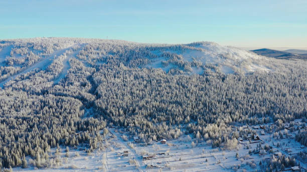 draufsicht auf das skigebiet am fuße des berges. filmmaterial. abgeschiedenes skigebiet am fuße des hügels mit skipisten ist in der wintersaison beliebt. klarer sonniger tag auf den skipisten des wintersportortes - ski trace stock-fotos und bilder