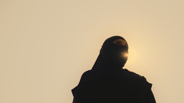 Muslim woman in Arab traditional dress wandering in desert, native land, sun