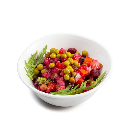 Vinaigrette salad with boiled vegetables, pickled cucumbers, sauerkraut and canned green peas in white bowl isolated on white. Traditional Russian snack. Vegetarian food. Side view.