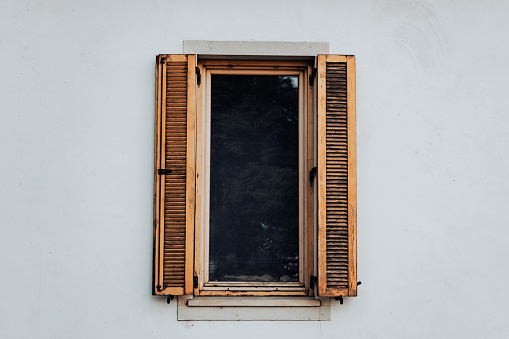 Vintage open window wood shutter on a white wall of a rustic home