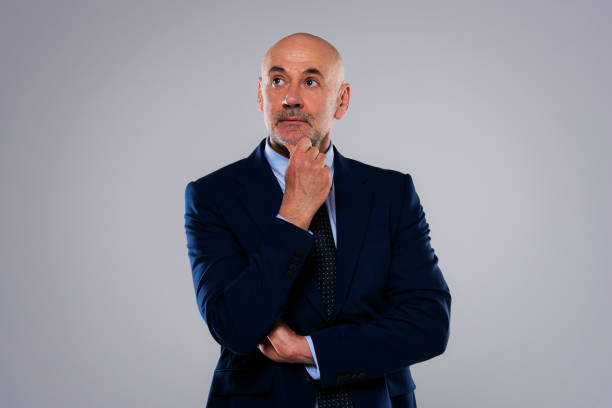 istock Studio portrait of thinking businessman standing at isolated background 1436472742