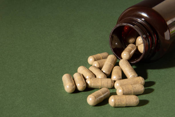 istock Herbal capsules are poured from a jar on a green background. 1436474177