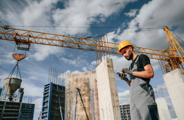 istock With phone in hands. Standing against crane. Man in uniform is working on the construction site 1436484002