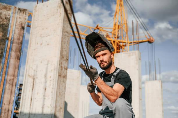 溶接マスクで。制服を着た男が建設現場で働いている - harsh lighting 写真 ストックフォトと画像