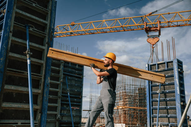 istock Yellow colored wooden plank. Man in uniform is working on the construction site 1436485227