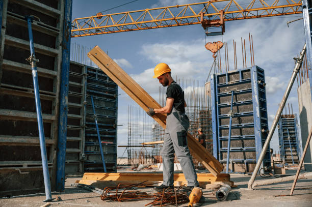 istock Placing wooden plank on the floor. Man in uniform is working on the construction site 1436485253