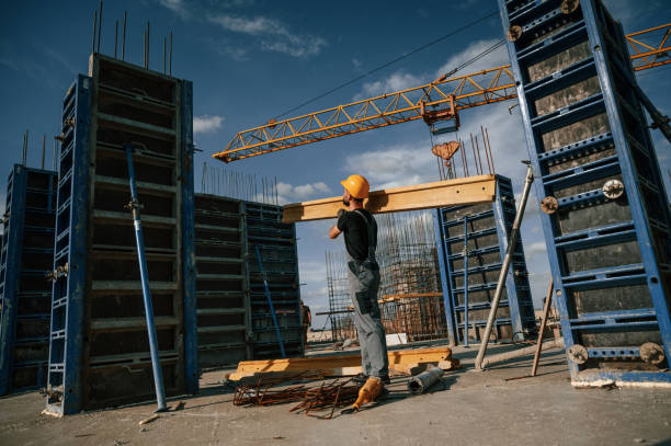 istock Yellow colored wooden plank. Man in uniform is working on the construction site 1436485264