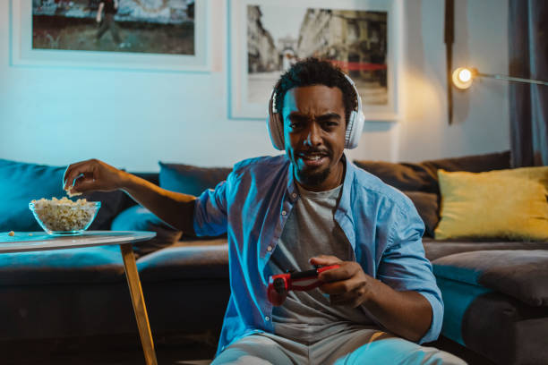 istock Young man playing video games at home and eating popcorn 1436487046