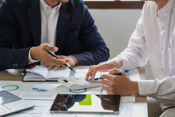 istock Team of business use calculators and graph analysis computer laptop tablets to plan marketing strategies and make profitable investments for the company. 1436489350