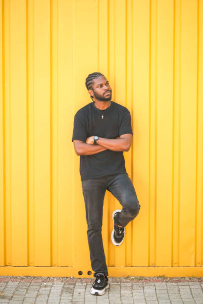 istock young black man with arms folded in front of yellow vertical striped background 1436491305