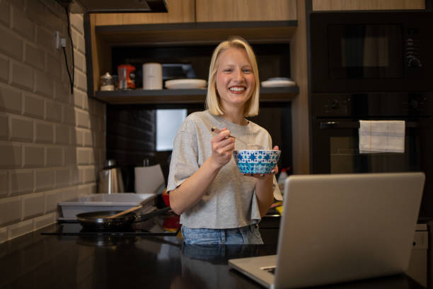 istock Beautiful young woman having breakfast in the kitchen 1436492172