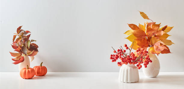 istock Home interior with decor elements. Colorful autumn leaves in a vase on a light background. Mock up for displaying works 1436497169