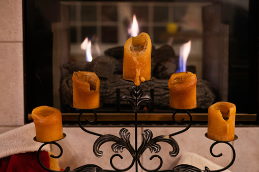 Christmas advent wreath in dark room in front of white cabinets with all four candles lit, red berries and evergreen boughs on wreath