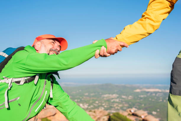 istock Helping hand - hiker man getting help on hike happy overcoming obstacle 1436497843